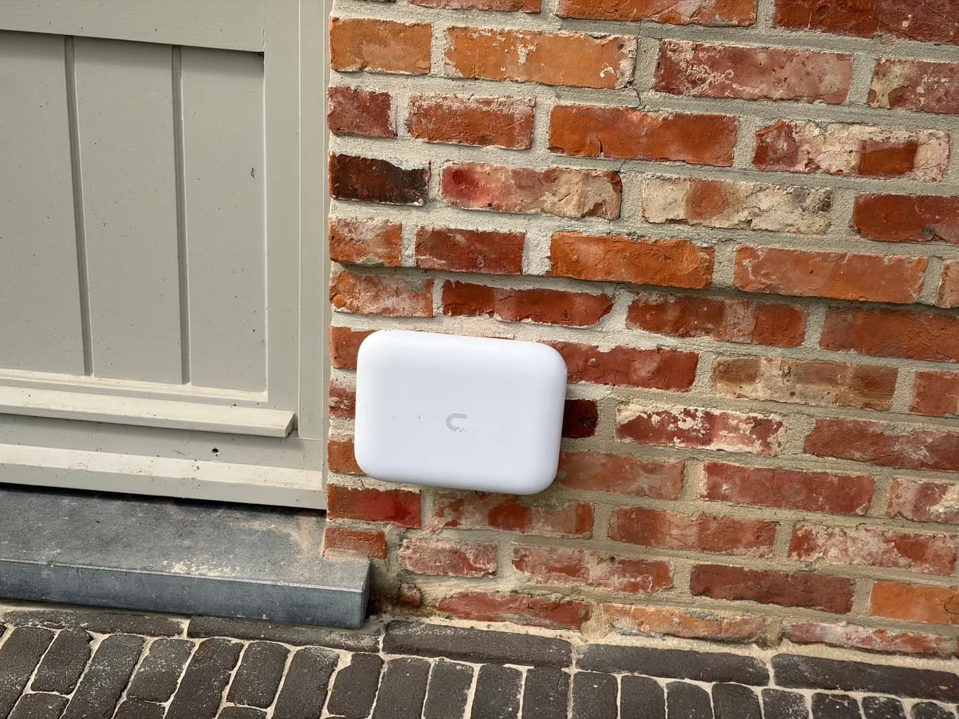 Borne Wi-Fi UniFi extérieure fixée sur une façade en brique